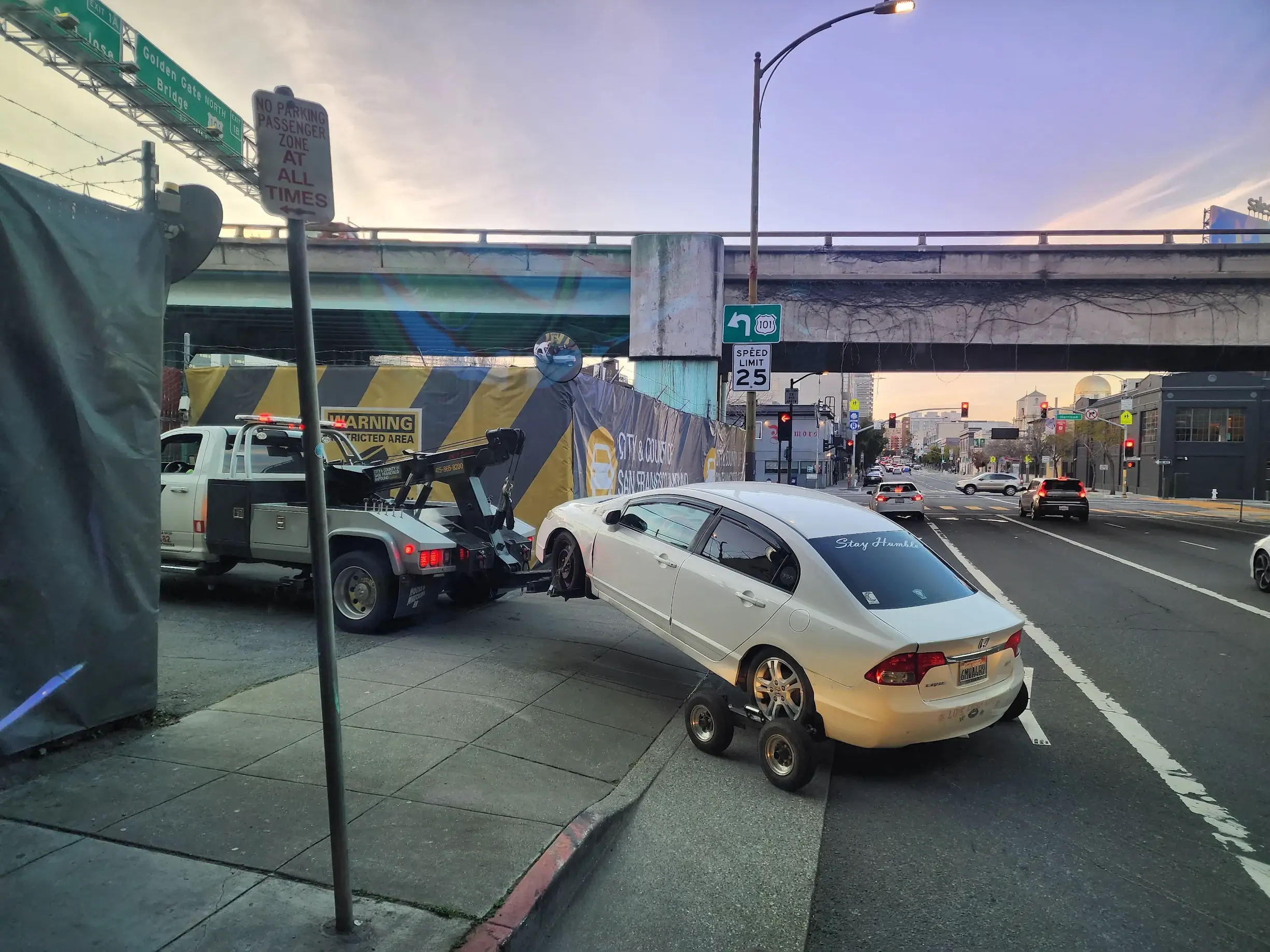 A white car is being towed by a tow truck.