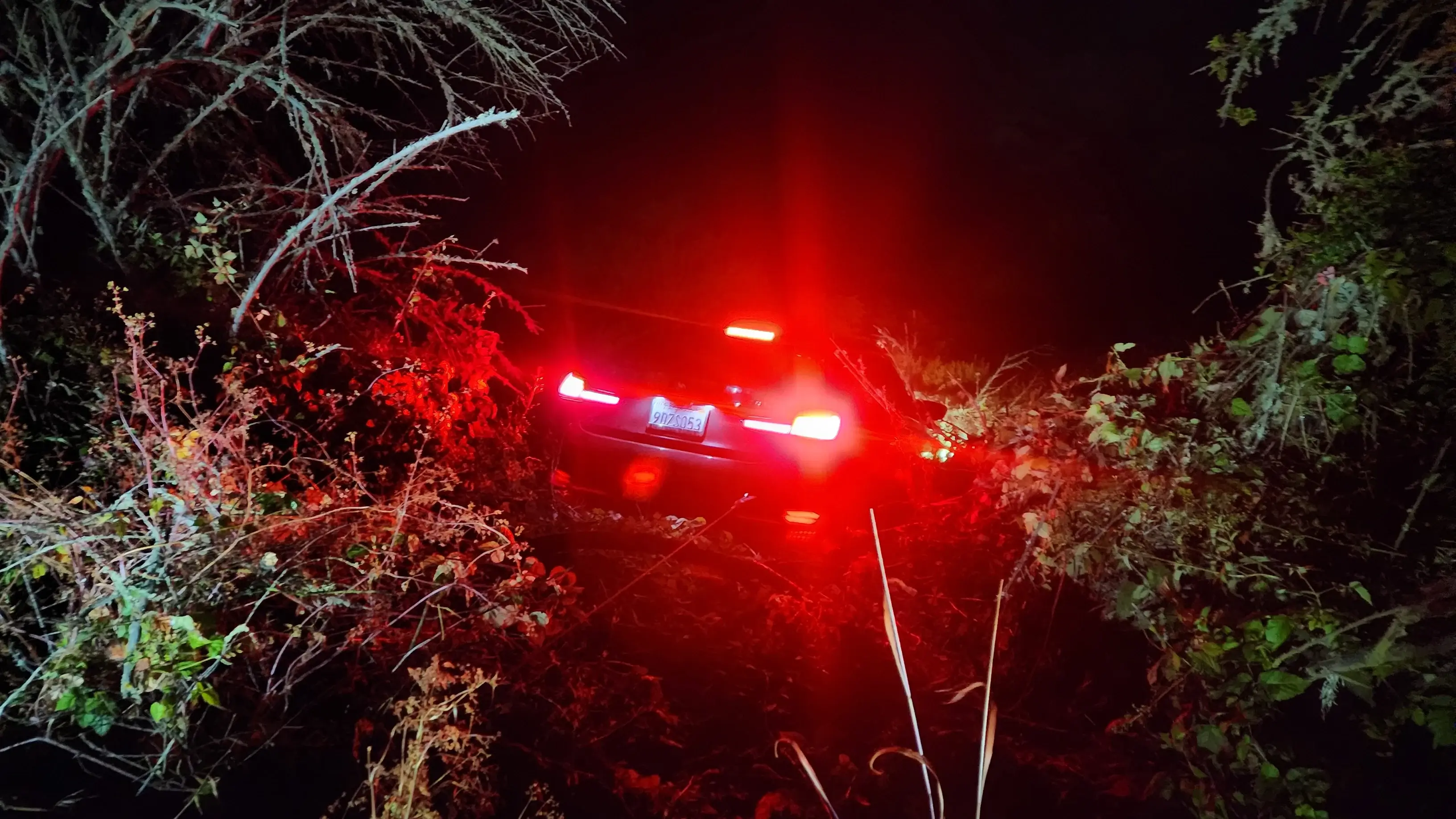 A car that is driving down the road at night.