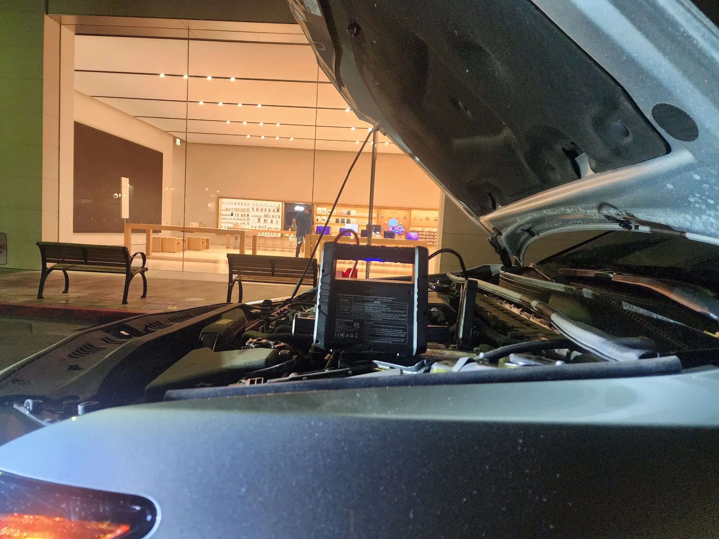 A car with the hood open and the battery hooked up to it.
