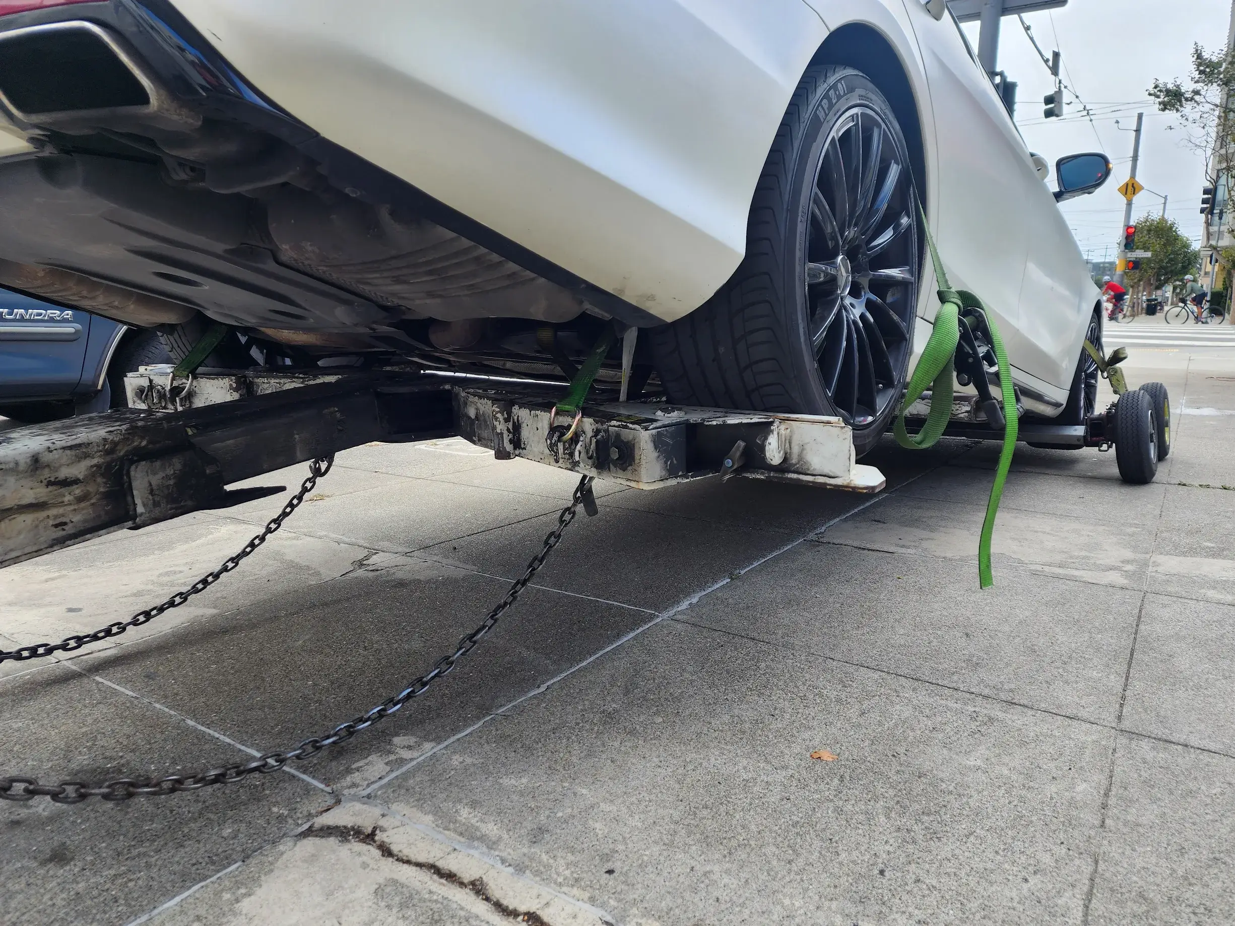 A white car is being lifted by chains.