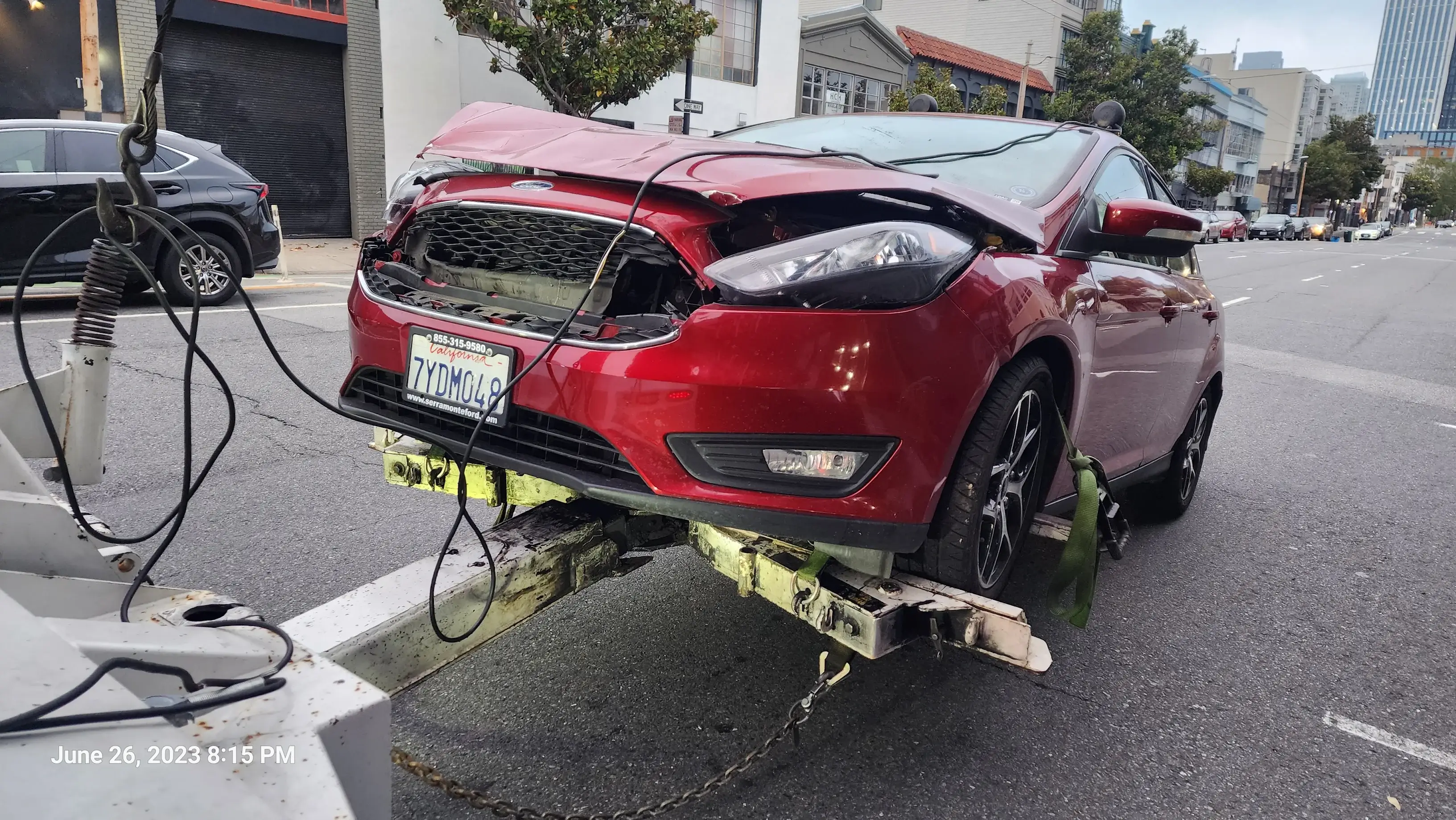 A red car that has been smashed on the side of the road.