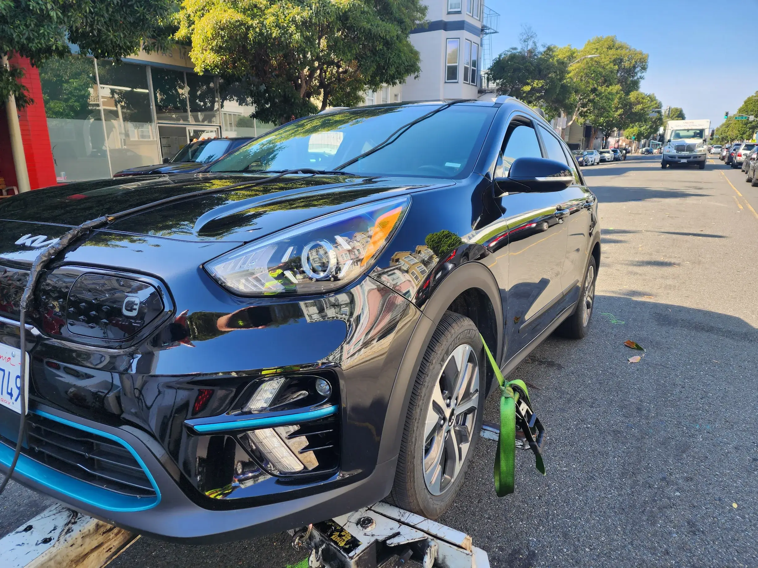 A blue car is parked on the side of the road.