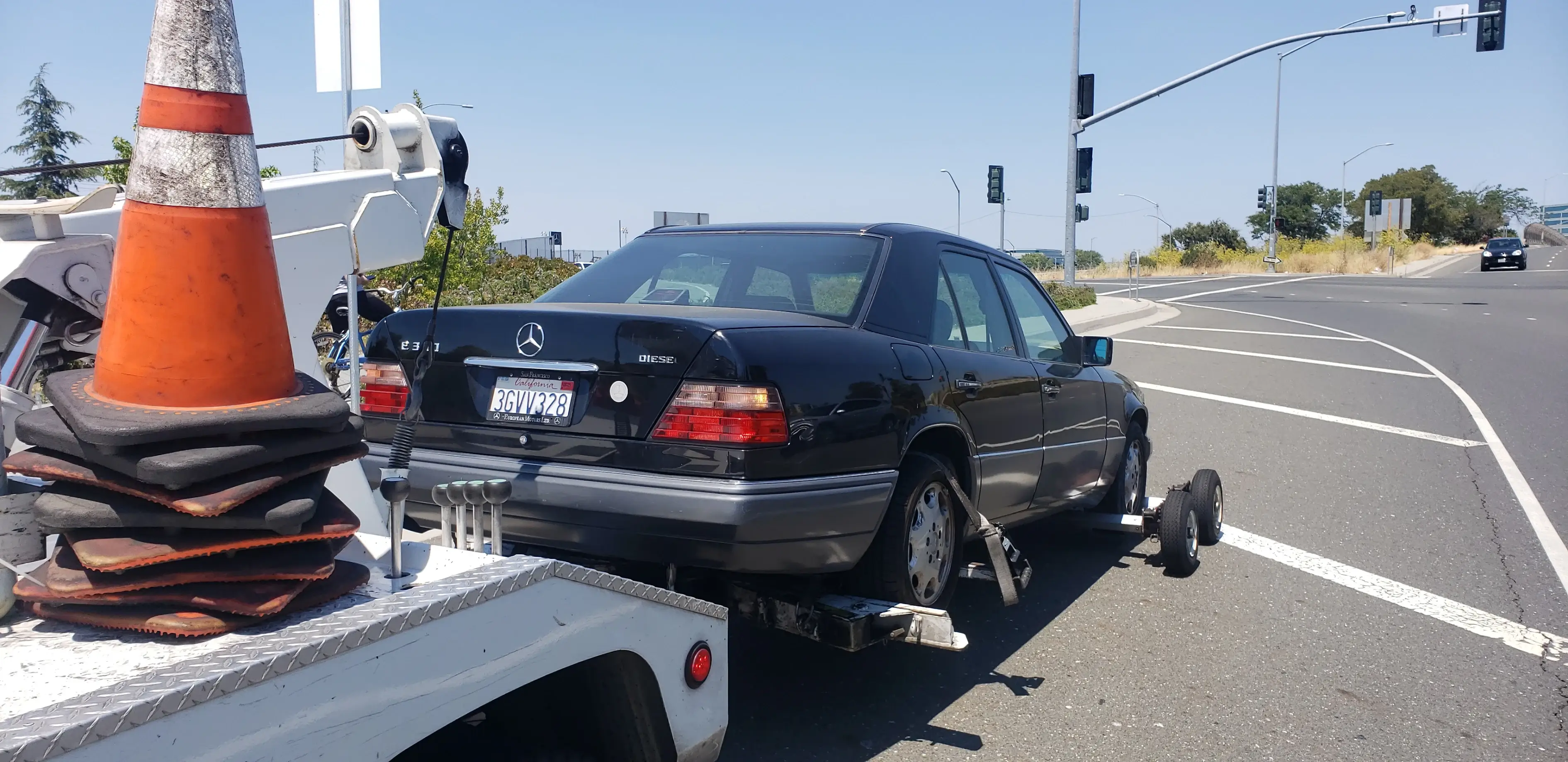 A black car is being towed by a white tow truck.