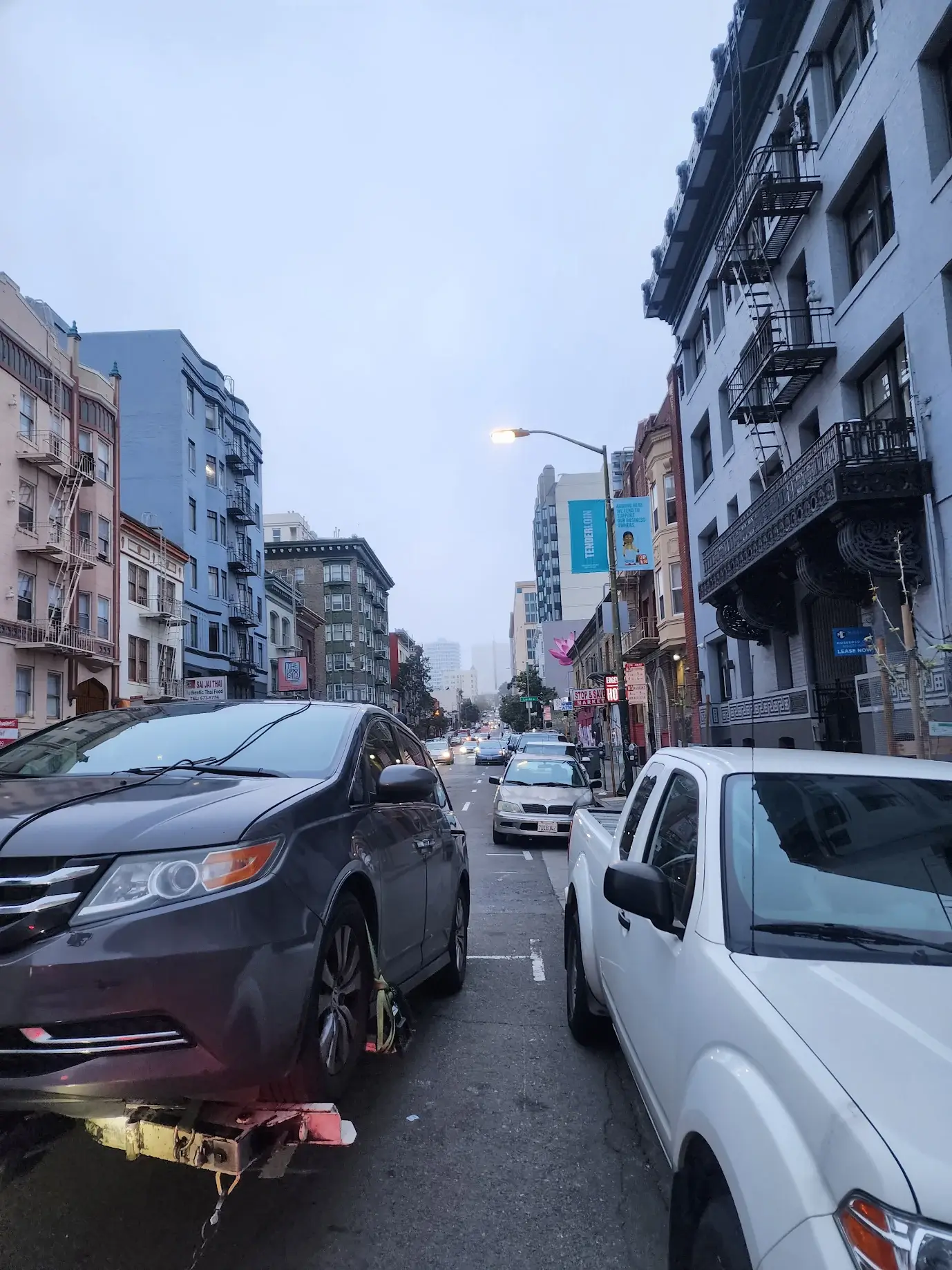A city street filled with traffic and parked cars.