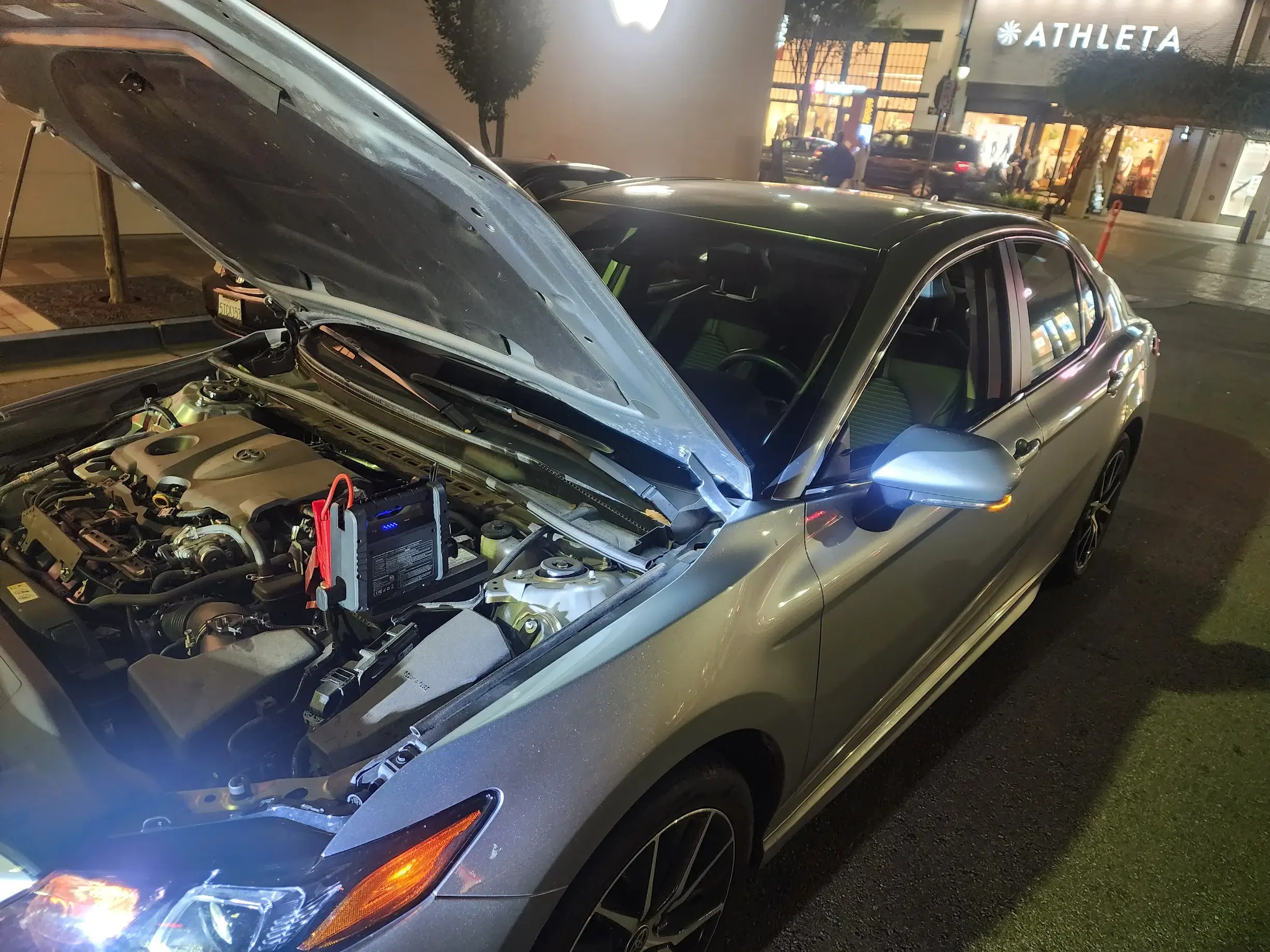 A silver car with its hood open and the engine bay exposed.